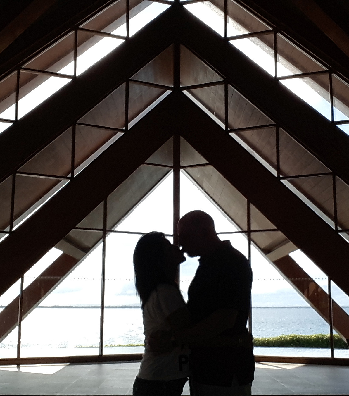 Maryvel and Lou sharing a kiss beneath a geometric wooden pavilion